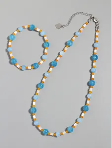 Detail of blue and orange beaded necklace set with silver heart charm on grey background