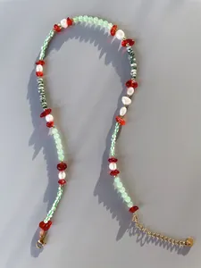Detailed shot of handmade necklace with red heart beads, pearls and green natural stones