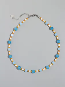 Close-up of blue and yellow stone beads necklace with silver heart charm and lobster clasp