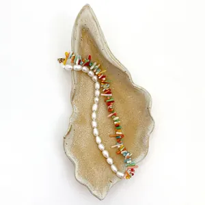 Dettaglio collana con perle barocche e grani colorati su vassoio in ceramica