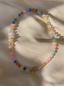 Macro detail of natural stones and pearls necklace with golden clasp on silk background