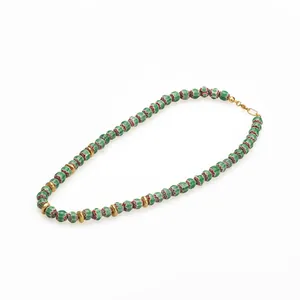 Détail de perles en verre millefiori et disques dorés sur un collier de perles bohème