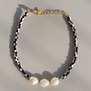 Macro view of checkered black and white beads with natural baroque pearls and gold clasp