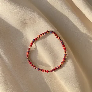 Macro detail of colorful resin beads and gold spacers on a handmade pearl bracelet