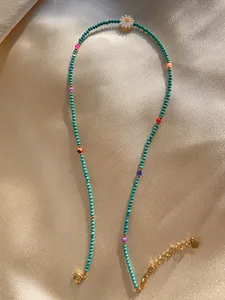 Macro shot of colorful natural stone beads and pearl necklace with small daisy pendant