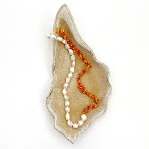 Dettaglio di perle d'acqua dolce e perle di corallo arancione su vassoio in ceramica