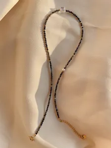 Detail of natural stone beads and freshwater pearl on a gold necklace clasp