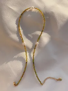 Close-up of olive green faceted beads and white freshwater pearls with gold clasp detail