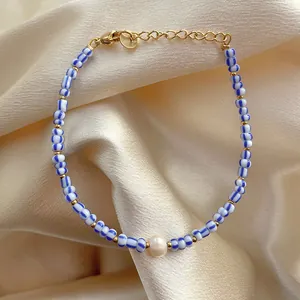 Detail of beaded bracelet with blue-white stripes, pearl center, and gold clasp