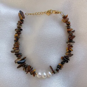 Macro view of handmade bracelet featuring brown tiger eye stones and white freshwater pearls