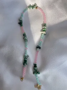 Detail of beaded necklace with pink, mint green beads and natural green stones on satin
