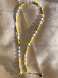 Detail of natural stone and freshwater pearl necklace on elegant champagne satin fabric