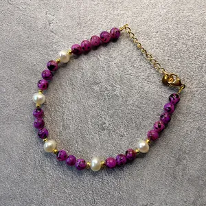 Dettaglio del bracciale con pietre di marmo viola, perle bianche e catena placcata in oro