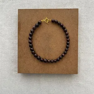 Collana in titanio placcato oro 18k con perle di granato rosso e chiusura a T di tendenza
