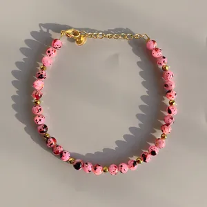 Detail of pink spotted beads and gold spacer beads on a handmade pearl bracelet