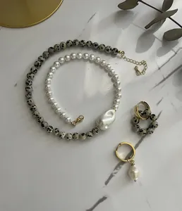 Detail of baroque pearl necklace with dalmatian stone beads on marble background