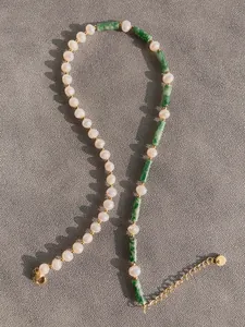 Detailed macro view of freshwater pearls and green stone beads with gold lobster clasp