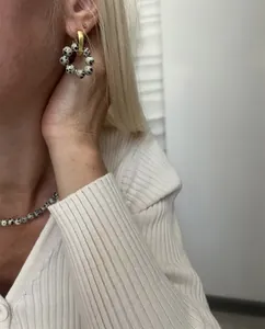 Detail of spotted stone drop earrings and matching gold necklace set on a model