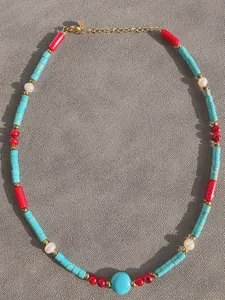 Detail of colorful necklace featuring turquoise beads, red stones and freshwater pearls