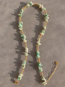 Close-up of handmade necklace with natural green stones and freshwater pearls with gold clasp