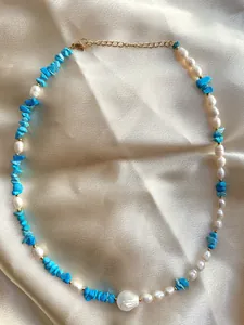 Detail showing natural turquoise stone and freshwater pearls on champagne silk fabric