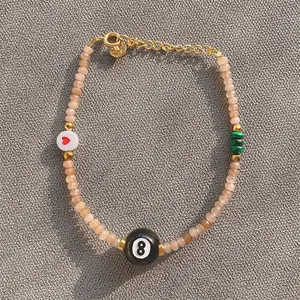 Detail of beaded bracelet with pink natural stones, 8-ball bead, and heart charm