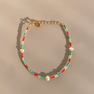 Detailed shot of handmade colorful beaded bracelet with white pearls and gold hardware