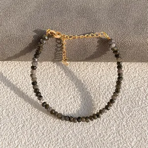 Detail of faceted grey natural stone beads and golden lobster clasp on handmade bracelet