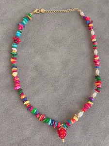 Close-up of vibrant beaded necklace with natural stones, pearls and a red strawberry charm