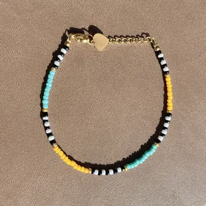 Detail of colorful beaded bracelet with gold heart charm and natural freshwater pearls