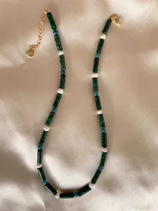 Close-up of handmade necklace with natural stones and pearls on champagne satin