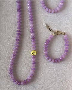 Detalle del conjunto de collar y pulsera de calcedonia púrpura con cuenta de cara sonriente