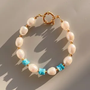 Detail view of handmade freshwater pearl bracelet with blue striped beads and gold clasp