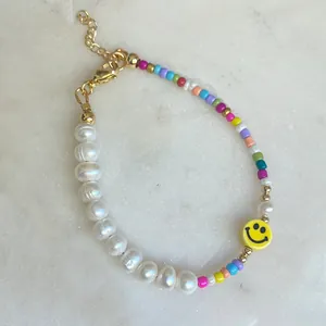 Close-up of glass bead bracelet with freshwater pearls and yellow smiley face charm