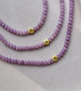 Detalle del collar de cuentas de calcedonia púrpura con una carita sonriente amarilla