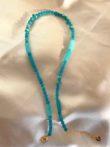 Detail of beaded necklace with blue natural stones and gold lobster clasp on silk