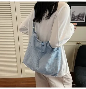 Detail of light blue textured tote bag with drawstring closure and adjustable strap