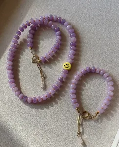 Detalle del conjunto de collar de cuentas de calcedonia púrpura con cierre dorado y smiley