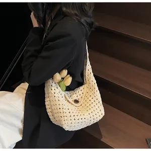 Detail der beige handgehäkelten Strandtasche mit hohlem Netzmuster auf Holzstufen