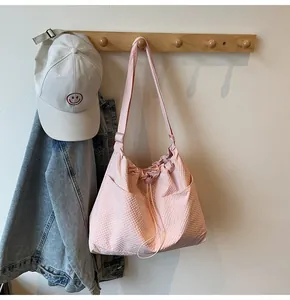 Detail of pink waffle-textured canvas tote bag with drawstring and side pocket