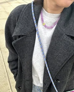 Detalle de collar de cuentas de calcedonia púrpura con cara sonriente y cordón tejido