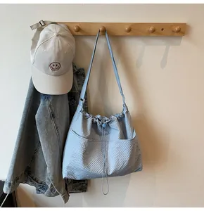 Detail of light blue textured canvas tote bag with drawstring and pockets on wall hook
