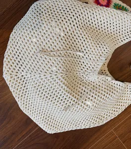 Close-up of beige hollow woven tote bag with drawstring and floral embroidery details