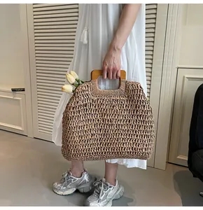 Détail d'un sac de plage en paille tissé main avec anses en bois carrées et fleurs