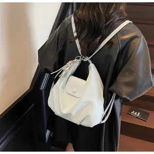 Detail view of the glossy pleated shoulder bag with star charm on a model's back