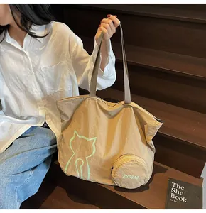 Detail of khaki tote bag featuring cat graphic print and a small round zipper pouch