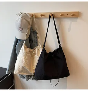 Detail of pleated nylon tote bags in beige and black on wooden hangers in home setting