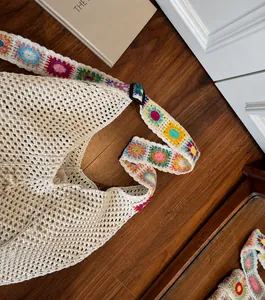 Detail of adjustable floral embroidered shoulder strap on off-white woven tote bag
