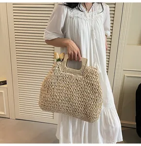 Détail d'un sac à main en paille tressée avec poignée en bois et décor de tulipes