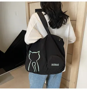 Detail of a large black canvas tote with green cat print and a small BUDBAO zipper pouch